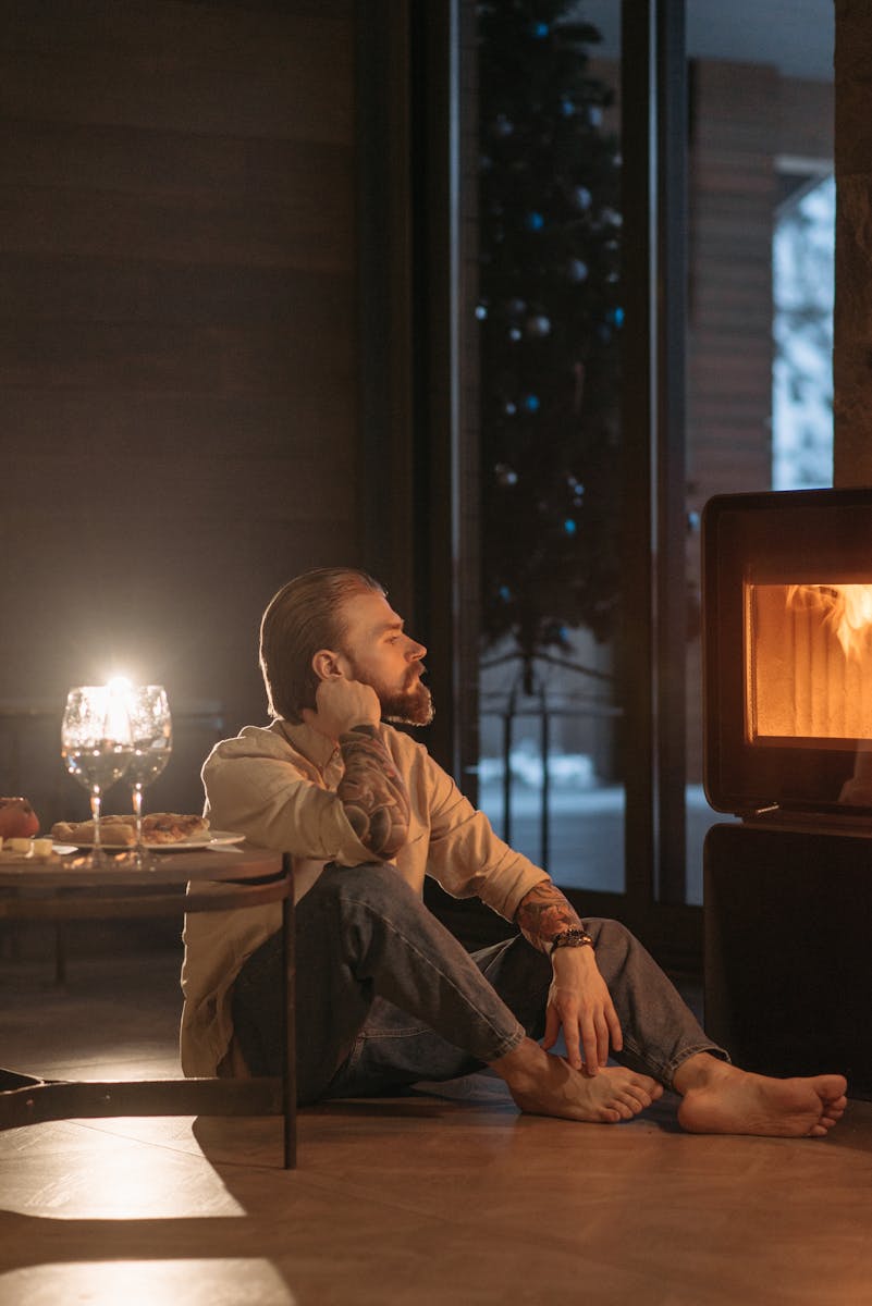 A contemplative man sits by the fireplace on a cold winter evening.